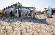Moderna Dune Lodge en EuroParcs Parc du Soleil en los Países Bajos, rodeada de arena y hierba de dunas.