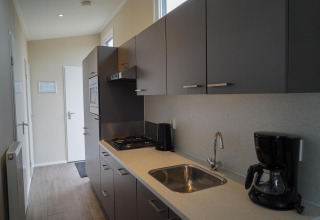 Moderne keuken in Dune Lodge bij EuroParcs Parc du Soleil in Nederland met koffiezetapparaat en gasfornuis.