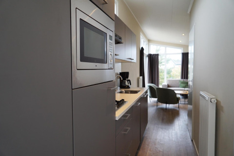 Moderne kitchenette in een Dune Lodge bij EuroParcs Parc du Soleil met uitzicht op de lichte woonkamer.