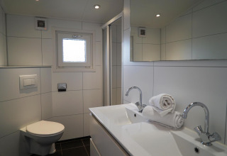 Baño moderno en Dune Lodge, EuroParcs Parc du Soleil, Países Bajos, con doble lavabo y aseo elegante.