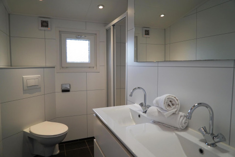 Baño moderno en Dune Lodge, EuroParcs Parc du Soleil, Países Bajos, con doble lavabo y aseo elegante.