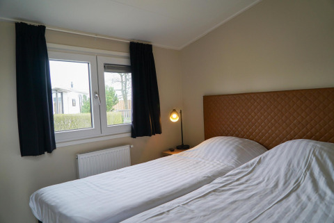 Chambre moderne avec deux lits simples et une fenêtre à Dune Lodge, EuroParcs Parc du Soleil, Pays-Bas.