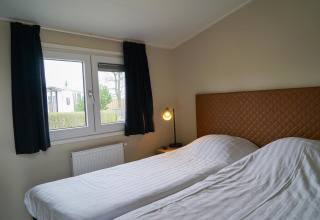 Chambre moderne avec deux lits simples et une fenêtre à Dune Lodge, EuroParcs Parc du Soleil, Pays-Bas.
