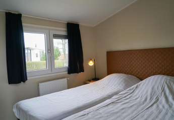 Modernes Schlafzimmer mit zwei Einzelbetten und Fenster in der Dune Lodge, EuroParcs Parc du Soleil.