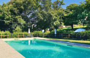 Piscine entourée d’arbres, de transats et de parasols au Camping Lucherino en Toscane, Italie.