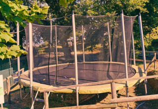Trampolino con rete di sicurezza tra gli alberi al Camping Lucherino, parco vacanze in Toscana, Italia.