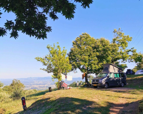Camping Lucherino en la Toscana, Italia, con autocaravana, árboles y vistas panorámicas del valle.