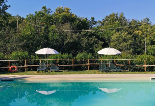 Piscina con lettini e ombrelloni al Camping Lucherino, parco vacanze in Toscana, Italia.