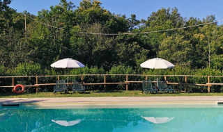 Piscina con tumbonas y sombrillas en Camping Lucherino, un parque vacacional en la Toscana, Italia.