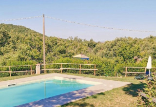 Piscina all'aperto con vista sulle colline e alberi verdi presso Camping Lucherino, parco vacanze in Toscana.