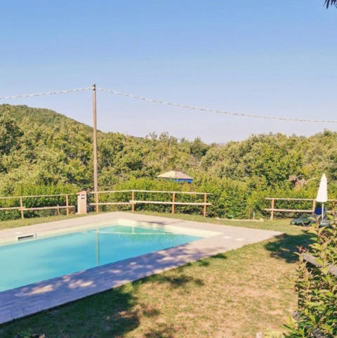 Buitenzwembad met zicht op heuvels en natuur bij Camping Lucherino, vakantiepark in Toscane, Italië.