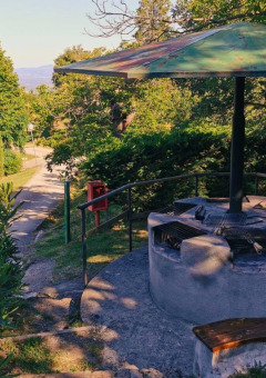 Área de barbacoa al aire libre en Camping Lucherino, Toscana, Italia, rodeada de bancas y vegetación.