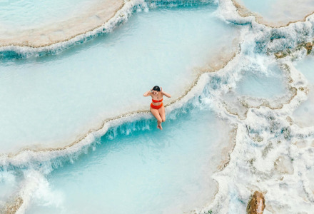 Mujer en bikini rojo disfruta de las piscinas termales cerca de Cinigiano, Toscana, Italia, vista aérea.