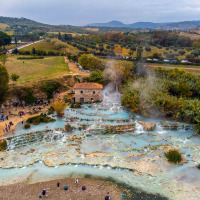 Aguas termales con bañistas cerca de Cinigiano, Toscana, Italia, rodeadas de vegetación y colinas.
