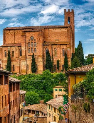 Vista de una iglesia histórica rodeada de vegetación y edificios antiguos cerca de Cinigiano, en la Toscana.