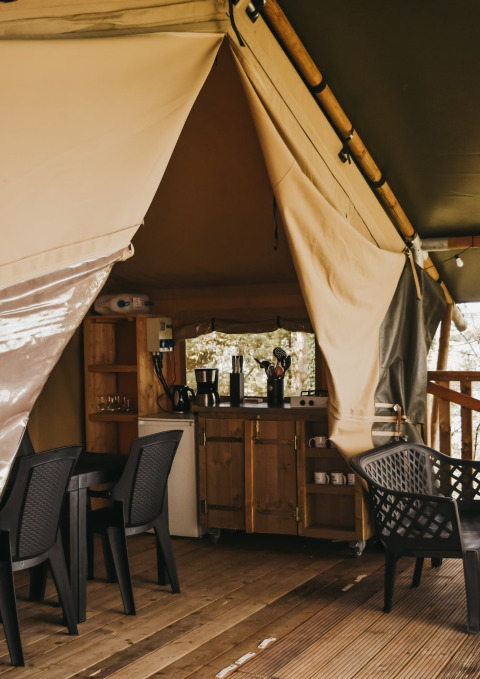 Intérieur de la Safari Tent Valley au Camping Lucherino en Italie, avec cuisine et coin repas.
