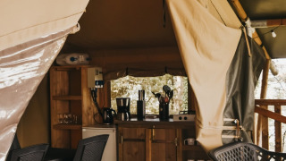 Interno di Safari Tent Valley al Camping Lucherino in Italia, con cucina e area pranzo visibili.