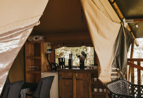 Interno di Safari Tent Valley al Camping Lucherino in Italia, con cucina e area pranzo visibili.