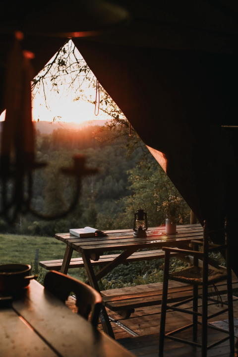 Sunset over the countryside as seen from a cozy outdoor dining area at Feather Down Rochefort-Ardenne, Belgium.