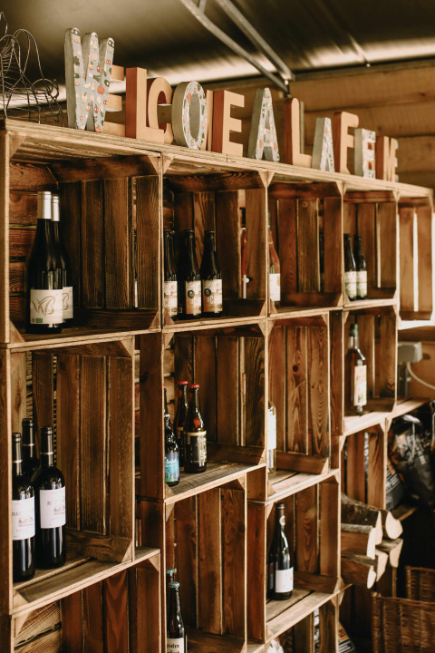 Estantes de madera con botellas y letras decorativas en Feather Down Rochefort-Ardenne, parque de vacaciones, Bélgica.