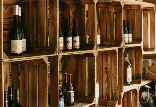 Houten rekken met flessen en decoratieve letters bij Feather Down Rochefort-Ardenne vakantiepark, België.