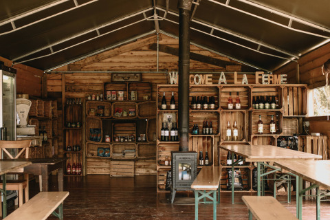 Acogedor interior de madera con estantes, productos locales y bebidas en Feather Down Rochefort-Ardenne.