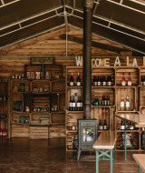 Indendørs marked med træmøbler, hylder med flasker og lokale varer hos Feather Down Rochefort-Ardenne.