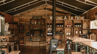 Acogedor interior de madera con estantes, productos locales y bebidas en Feather Down Rochefort-Ardenne.