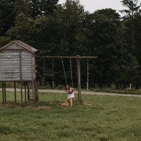 Una niña juega en un columpio junto a una casita de madera en un campo cerca de Nassogne, Luxemburgo, Bélgica.