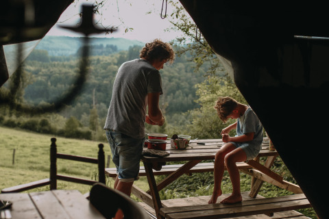 Twee personen genieten van buitenactiviteiten aan een picknicktafel met boszicht bij Rochefort-Ardenne.