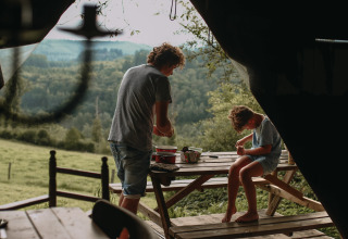 Twee personen genieten van buitenactiviteiten aan een picknicktafel met boszicht bij Rochefort-Ardenne.