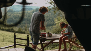 Dos personas disfrutan de actividades al aire libre en una mesa de picnic con vistas al bosque en Rochefort-Ardenne.