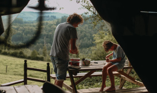 To personer nyder udendørs aktiviteter ved et picnicbord med smuk udsigt over skovene i Rochefort-Ardenne.