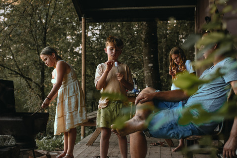 Familie nyder udendørs tid på en hytteveranda i Feather Down Rochefort-Ardenne, Belgien Luxembourg.