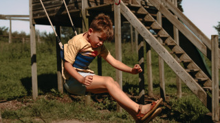 Niño columpiándose al aire libre en el parque infantil del Feather Down Rochefort-Ardenne en Bélgica.