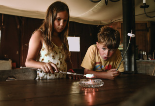 Deux enfants font griller des marshmallows à l’intérieur au Feather Down Rochefort-Ardenne, Belgique.
