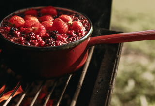 Ein Topf mit frischen Beeren, darunter Erdbeeren, kocht über offenem Feuer in Rochefort-Ardenne.