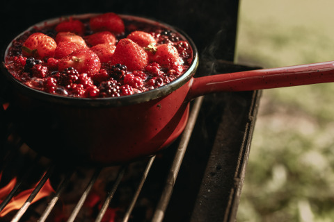 Una olla de frutos rojos frescos, incluidas fresas, hirviendo sobre fuego en Feather Down Rochefort-Ardenne.
