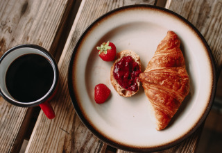 Een bord met croissant, aardbeien, brood met confituur en een tas koffie bij Feather Down Rochefort-Ardenne.