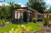 Moderne lodge Cannenburch met parasol en tuinmeubels in Veluwepark de Bosgraaf, Nederland.