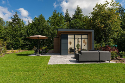 Lodge moderno con grandes ventanales, patio y muebles de jardín en Veluwepark de Bosgraaf, Países Bajos.