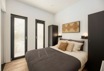 Modernes Schlafzimmer mit Doppelbett, schwarzen Schränken und großen Fenstern bei Cannenburch, Veluwepark de Bosgraaf.