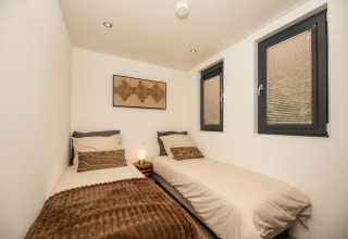 Twee eenpersoonsbedden in een gezellige kamer van het Cannenburch-lodge, Veluwepark de Bosgraaf, Nederland.
