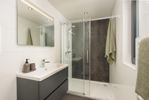 Moderne badkamer met douche en spiegel in Cannenburch, Veluwepark de Bosgraaf, Nederland.