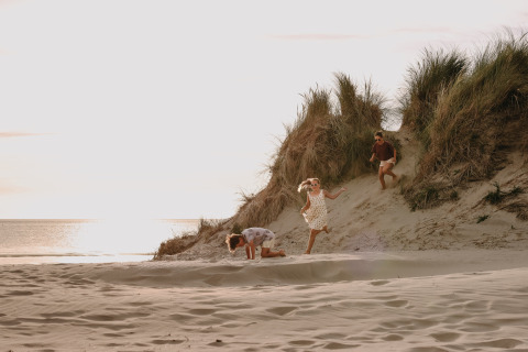 Niños jugando en las dunas de arena en Feather Down Boerderij Ameland, un parque vacacional en Frisia, Países Bajos al atardecer.