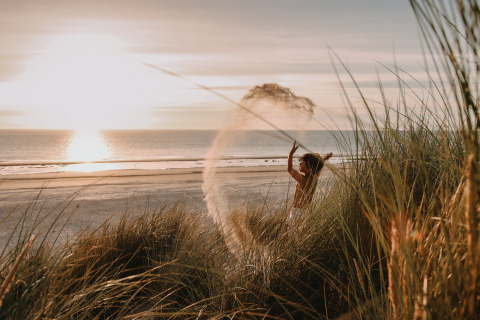 Bambino gioca tra le dune al tramonto sulla spiaggia di Feather Down Boerderij Ameland, Friesland, Paesi Bassi.