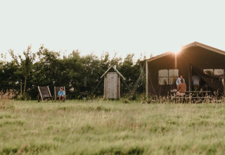 Et fredeligt øjeblik på Feather Down Boerderij Ameland, med børn der leger udenfor ved en feriepark.