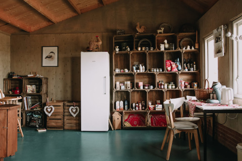 Cocina rústica con cajas de madera, nevera y comedor en Feather Down Boerderij Ameland, Friesland, Países Bajos.