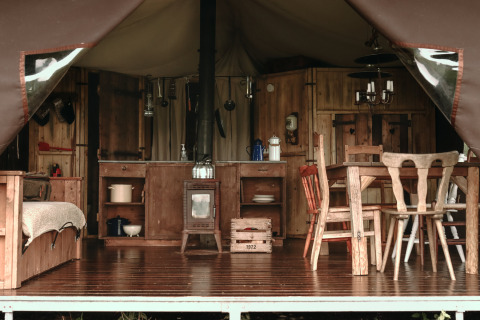 Vista interior de una tienda rústica con cocina y comedor en Feather Down Boerderij Ameland, Frisia, Países Bajos.