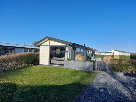 Chalet Velthorst au EuroParcs Parc du Soleil, Pays-Bas, pelouse verte, haies et ciel bleu ensoleillé.